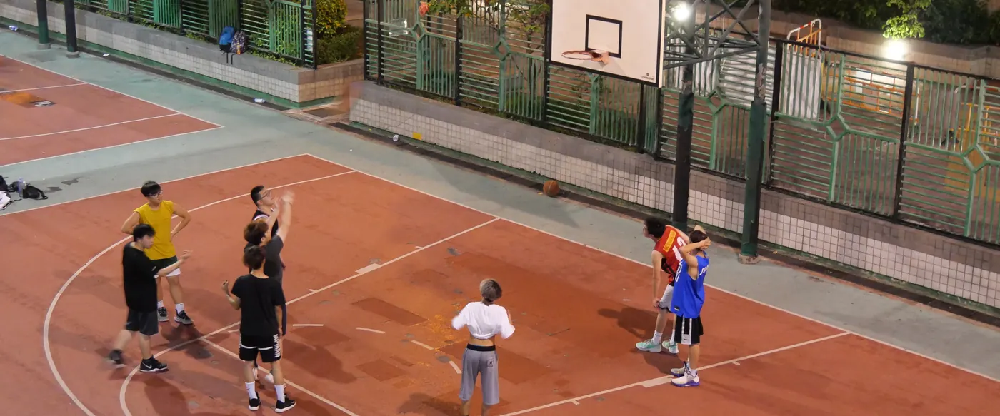 A pickup basketball game under floodlights on an outdoor court