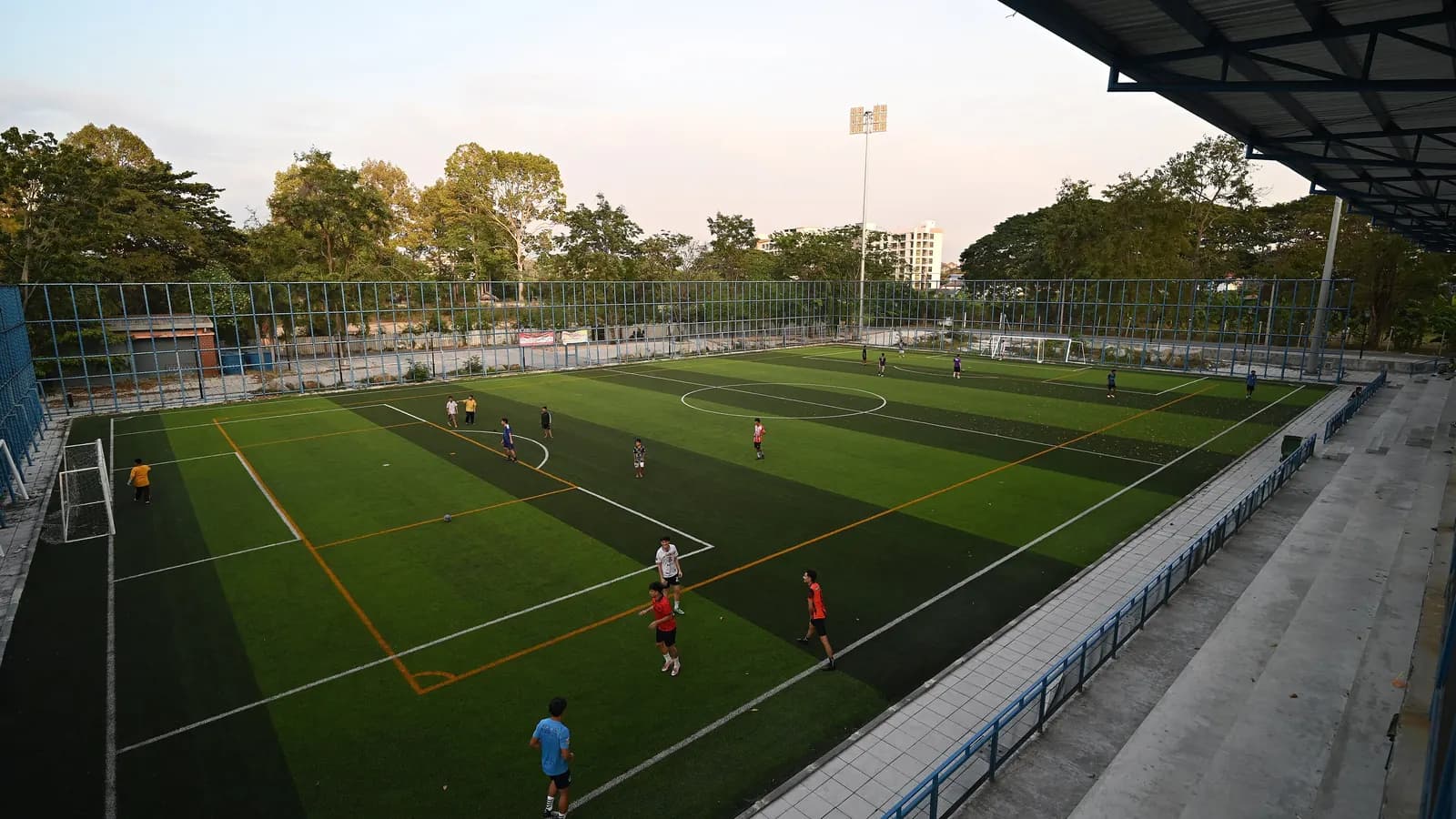 Floodlit sports pitch in the evening with people playing